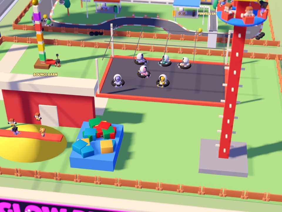 The Fun Yard: bumper cars on a dark floor, a tall red drop tower, a red barn and a bouncy castle